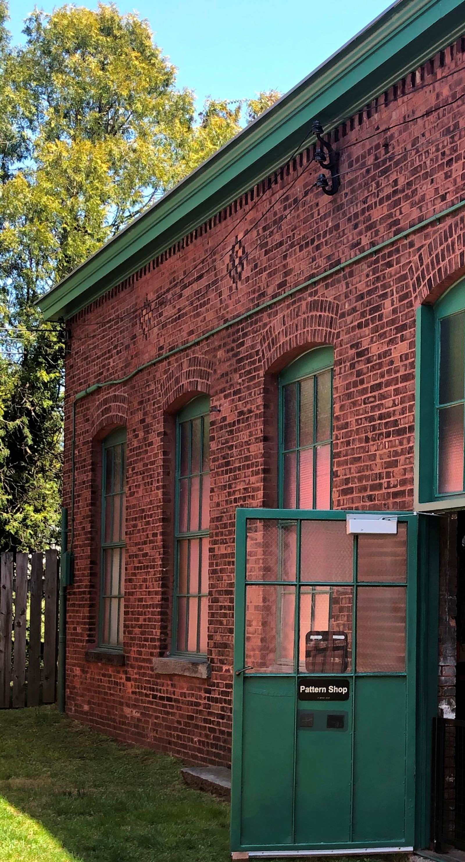 Rectangular, red brick building with green opened door.