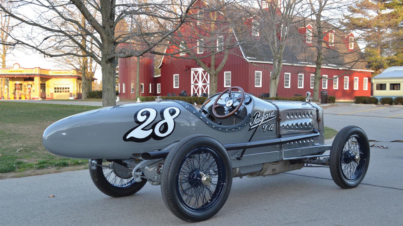 Vintage car at an automobile museum in front of red barn.