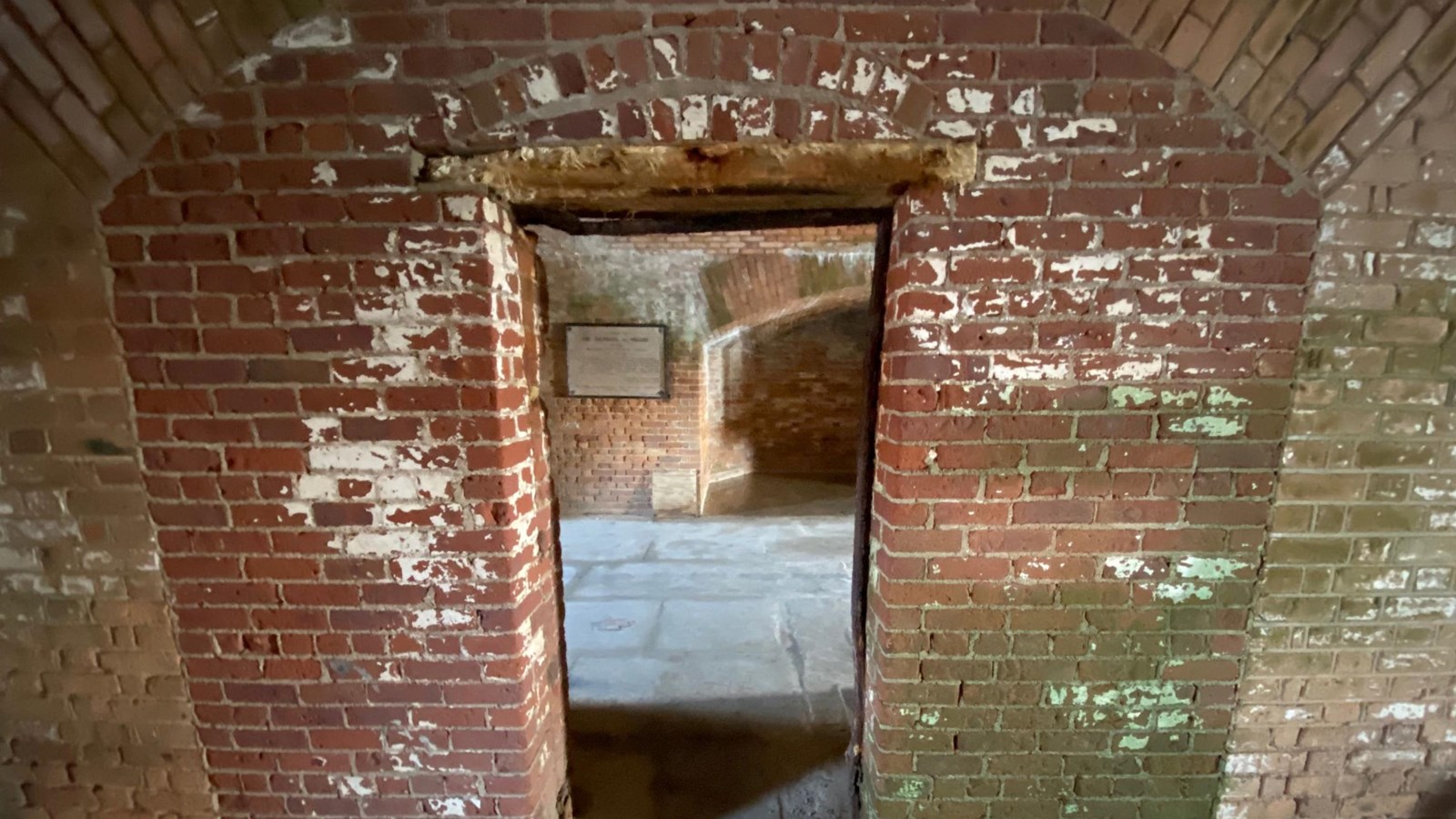 A brick doorway leads to a dark and gloomy room.
