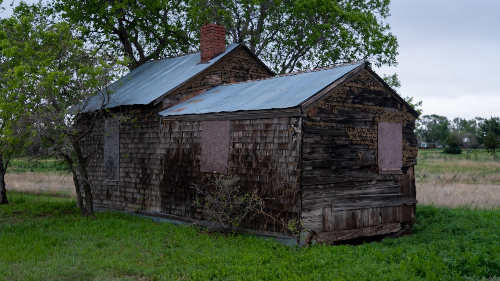 A small house with corrugated steel roof, and wooden siding.