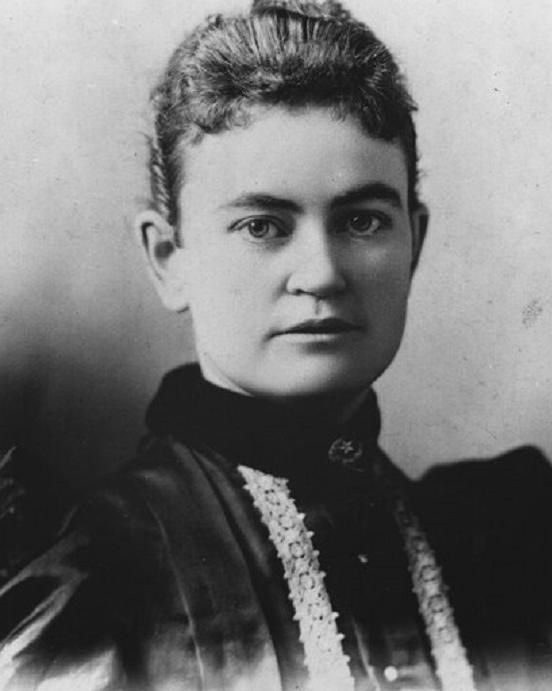 Head and shoulders portrait of a young woman wearing a black dress.
