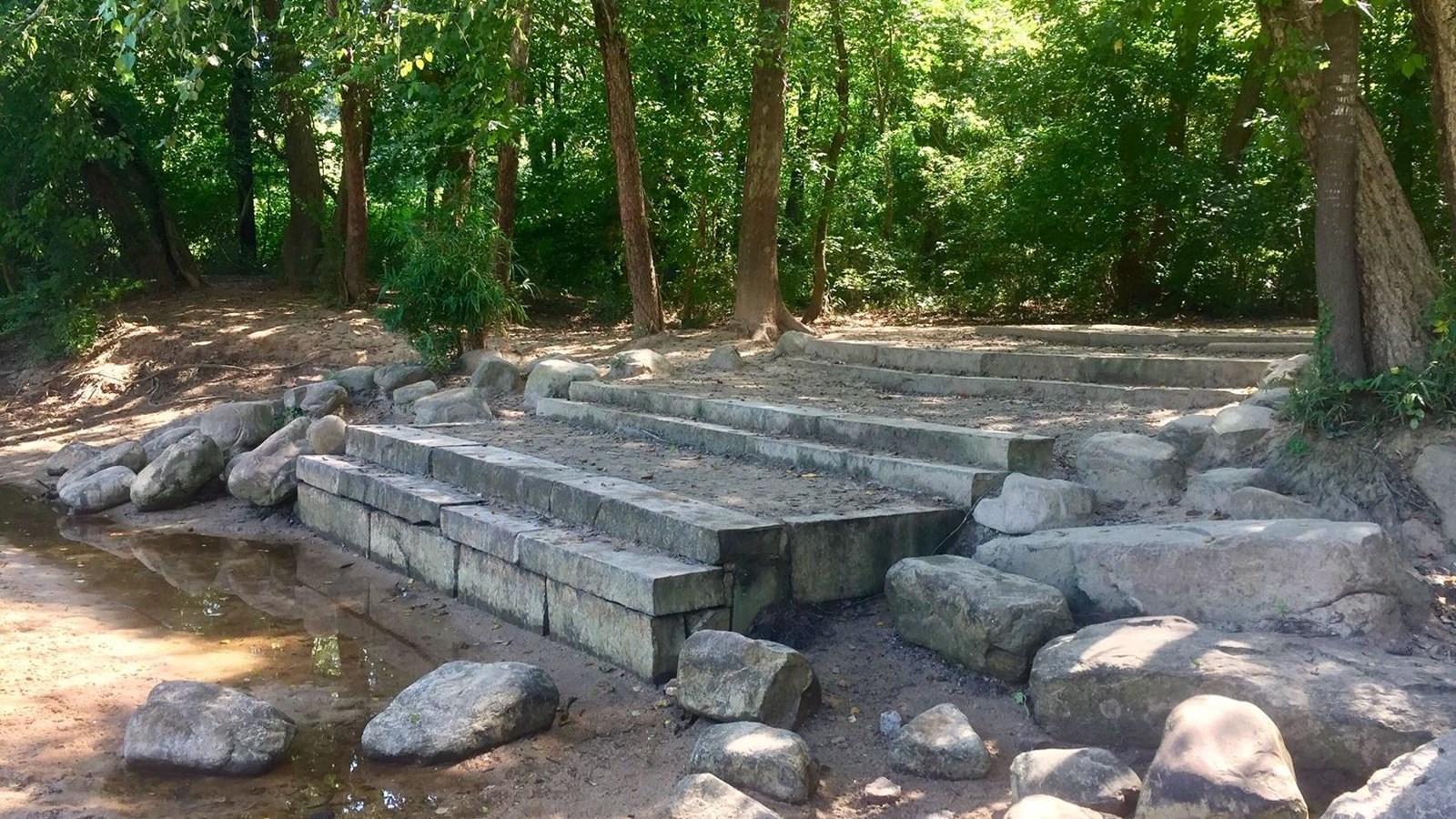 View of steps down to the rivers edge with woods in the background.