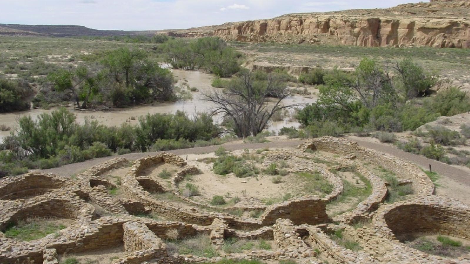 Remnants of the walls of a tri-wall kiva in front of an arroyo with high water level.