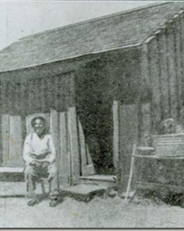 Man sitting outside of a small house
