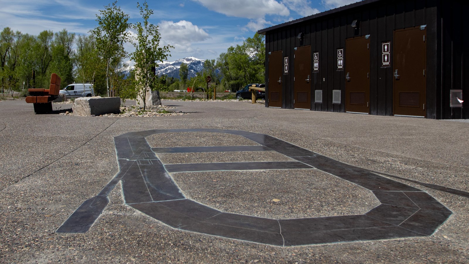 A bronze outline of a raft sits in concrete with bathrooms and other concrete features.