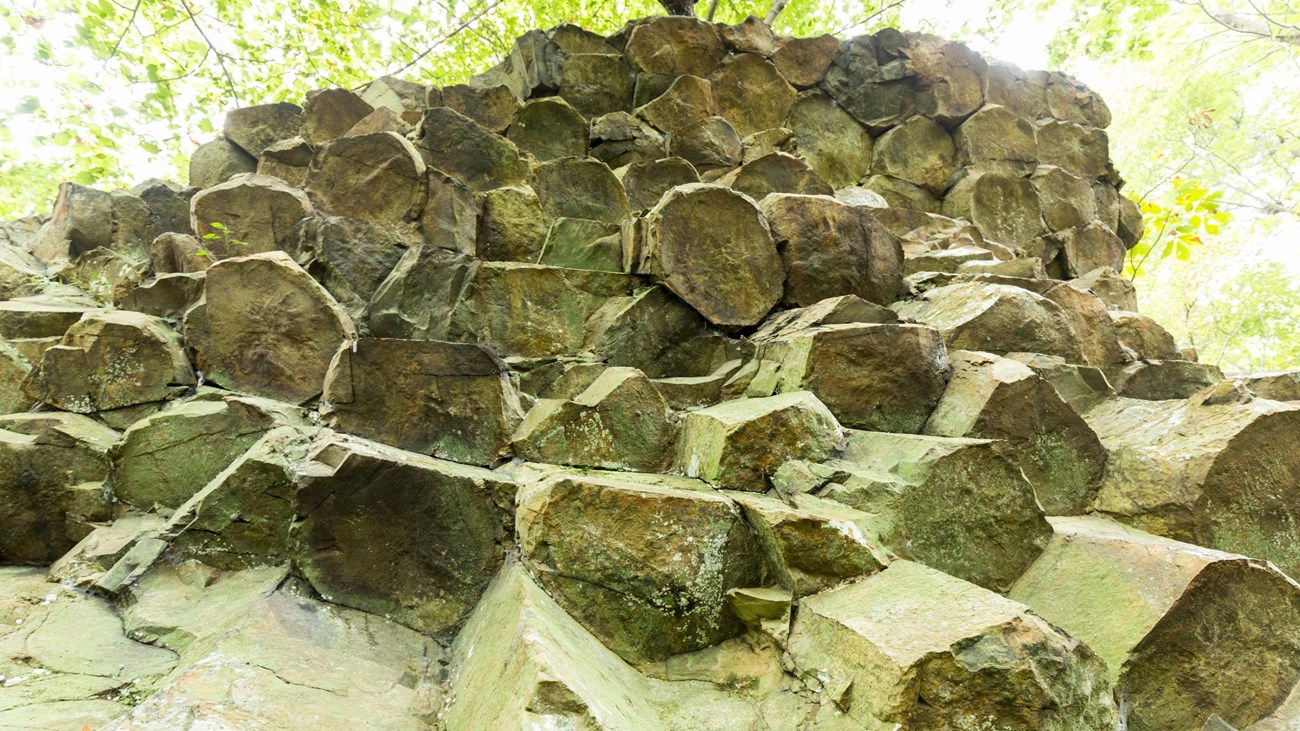 A cliff of rocks, shaped like pentagons, stands above