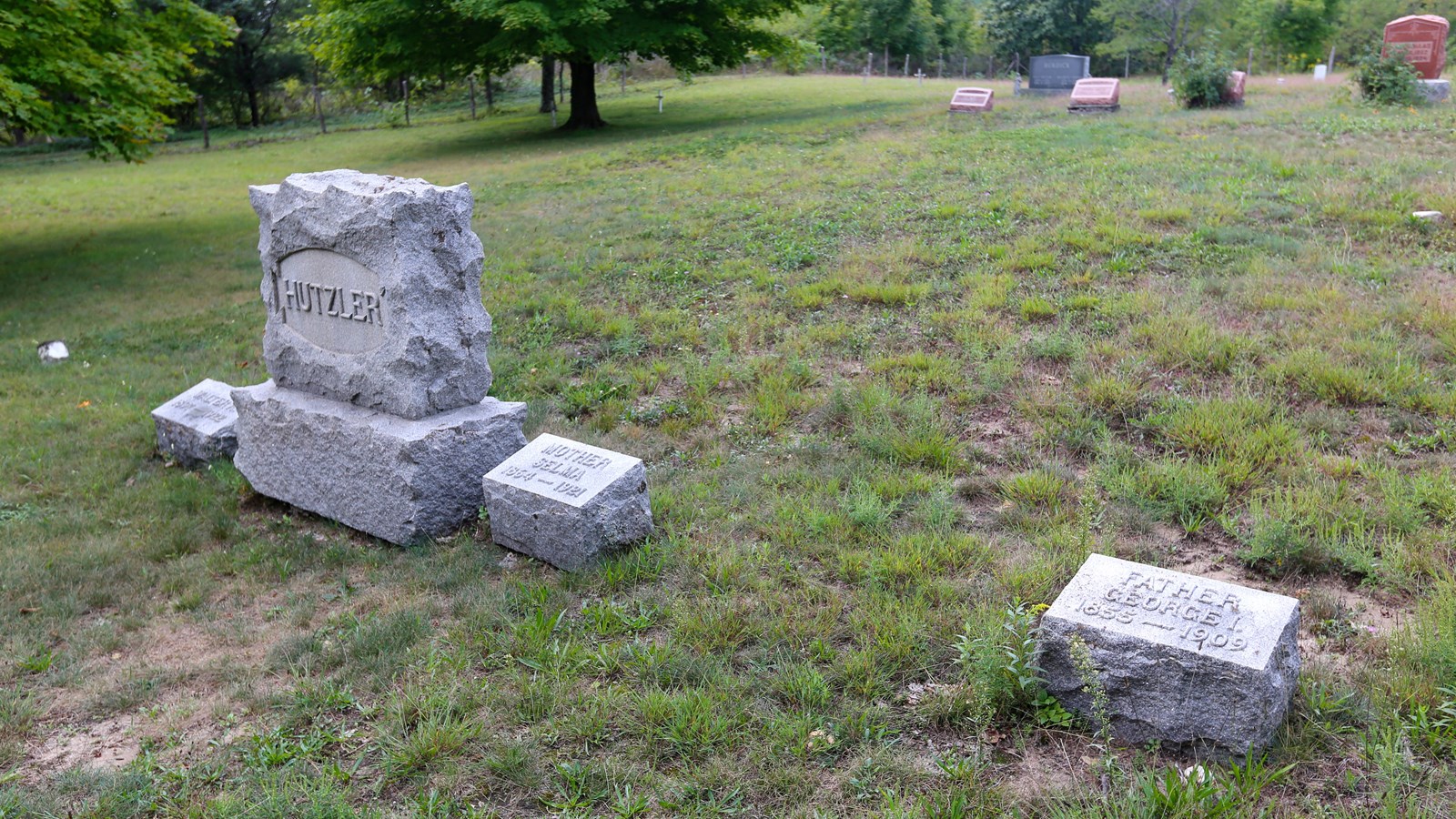 Four gray headstones in grassy field