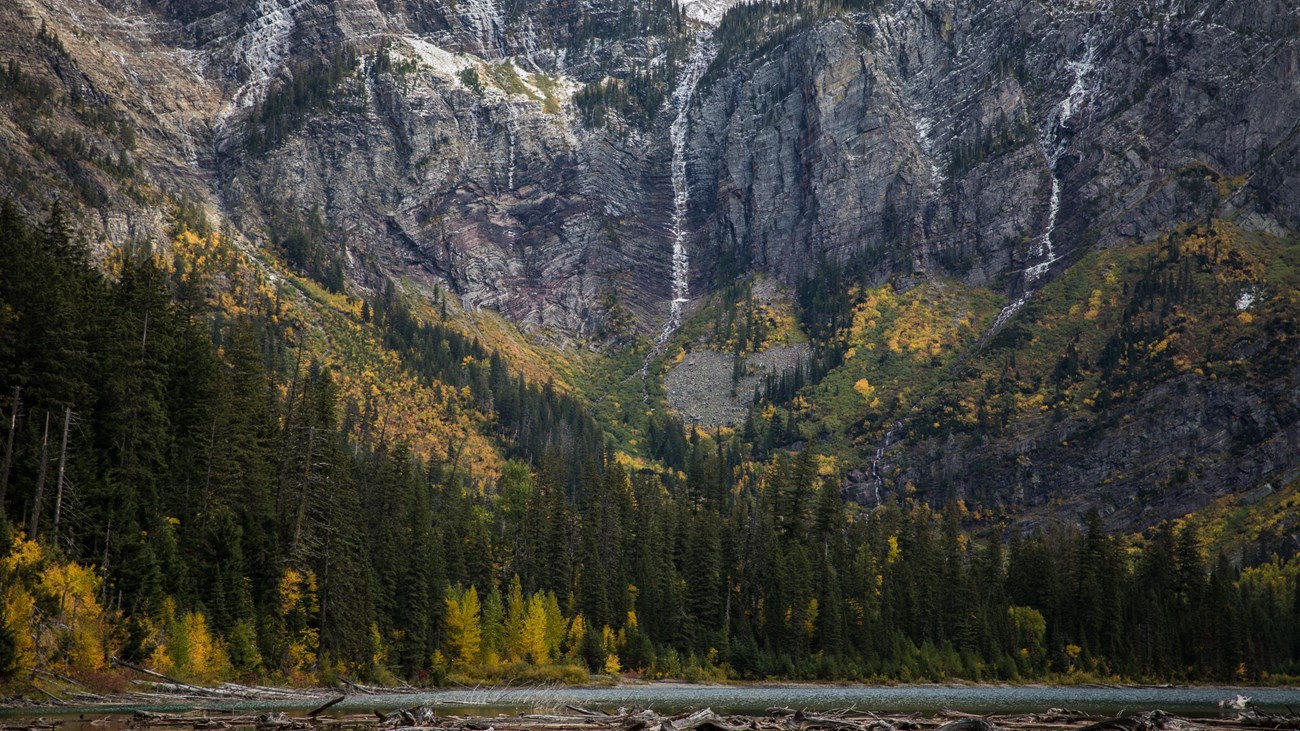 A first dusting of snow decorates the rocky peaks above the fall colors of the mountain lake basin.