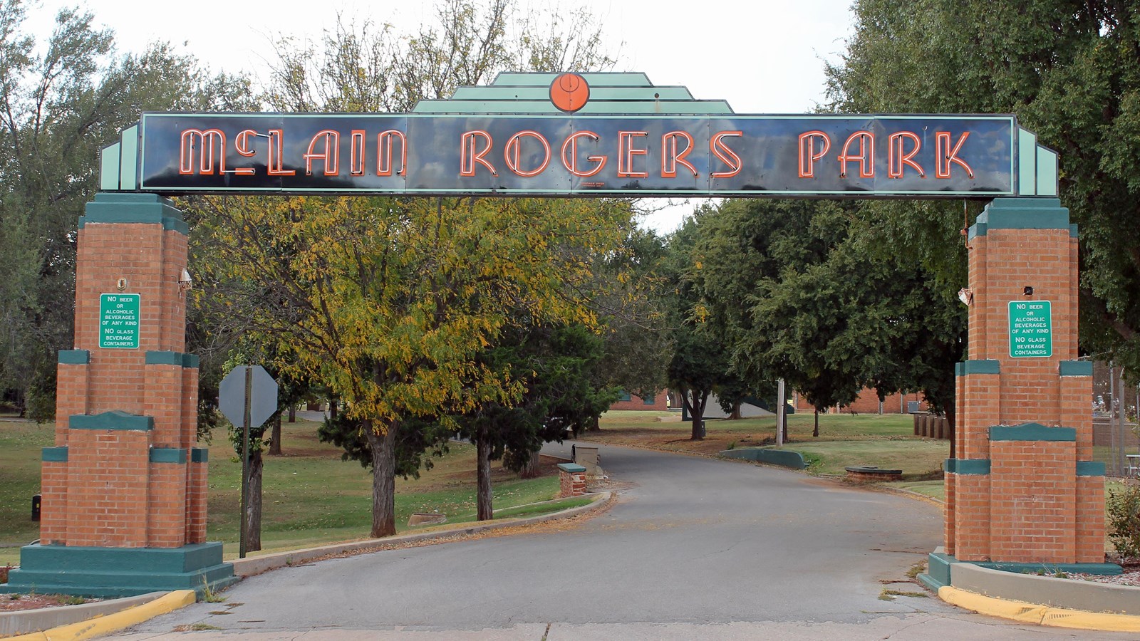 A blue sign with red text, held up with large brick pillars. The sign reads 