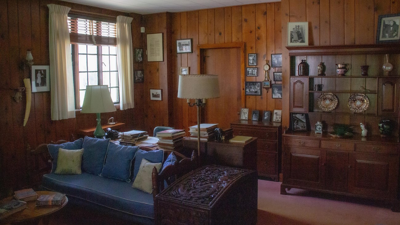 A living room with large desk near a fireplace.