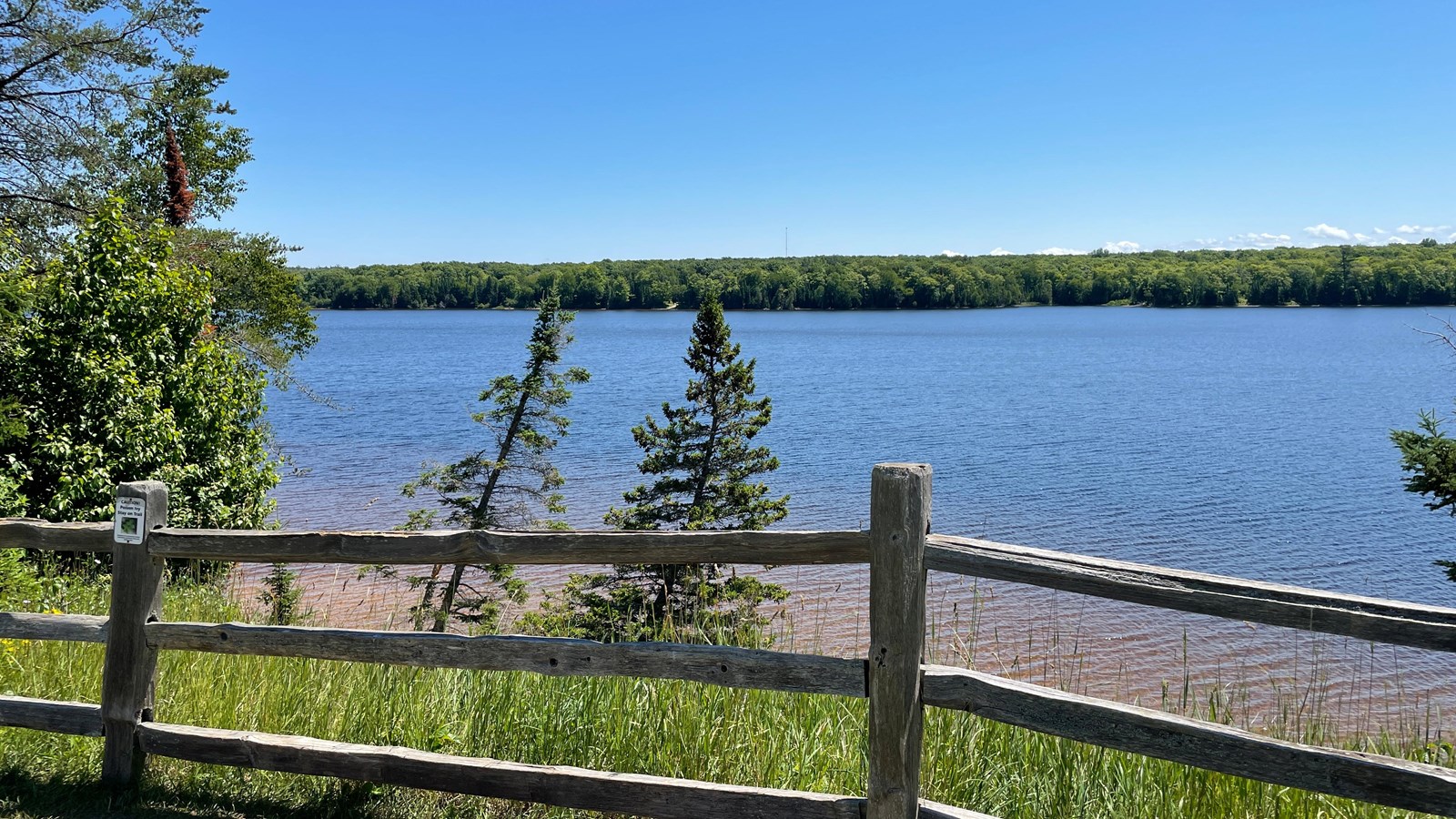 Wooden fence along picnic area with lake in the distance
