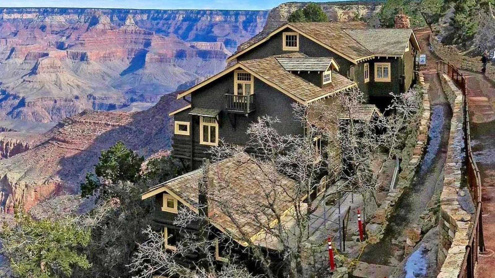 a rambling multi-story craftsman style wood frame building perched on the edge of a canyon cliff.