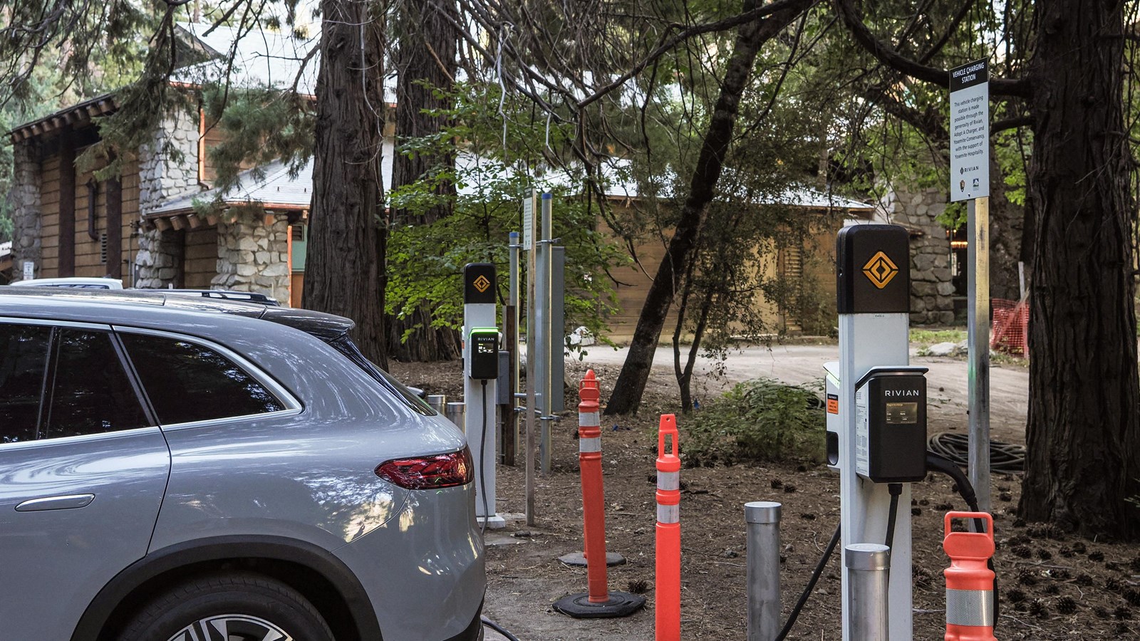 A vehicle plugged into a charging station in a parking area with a large hotel in the background