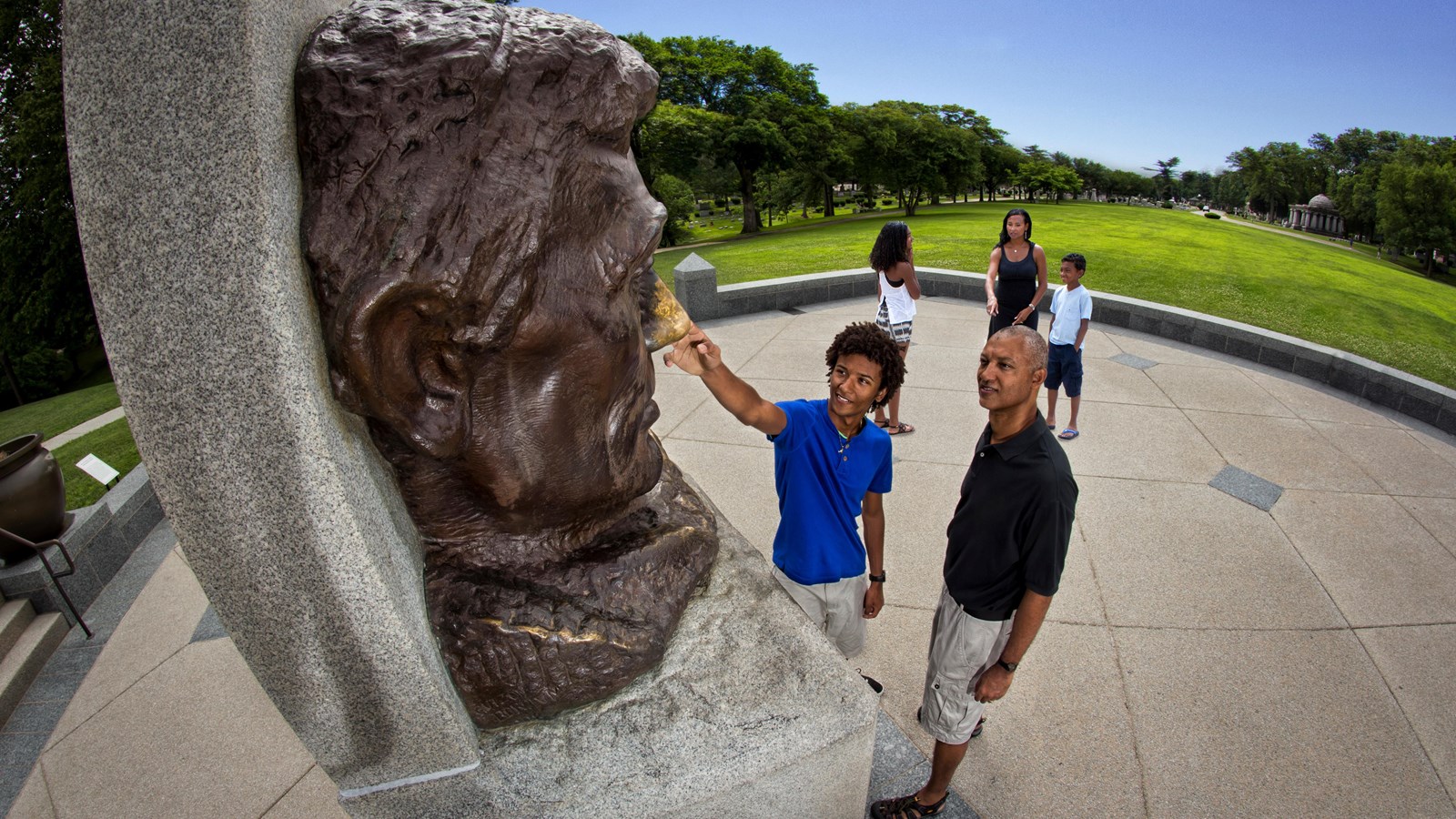 Family visiting Lincoln\'s Tomb State Historic Site and rubbing Abraham Lincoln\'s nose of a large bus