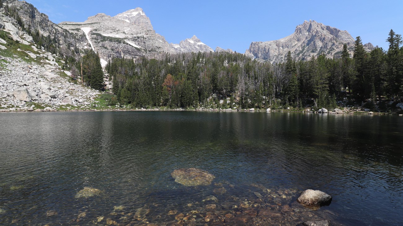An alpine lake sits beneath rocky mountain peaks.