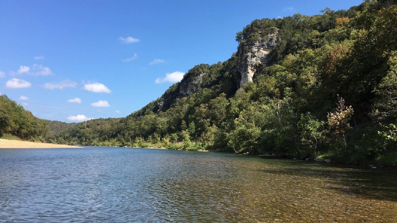 The river flanked by a bluff on the right side and a gravel bar on the left side.