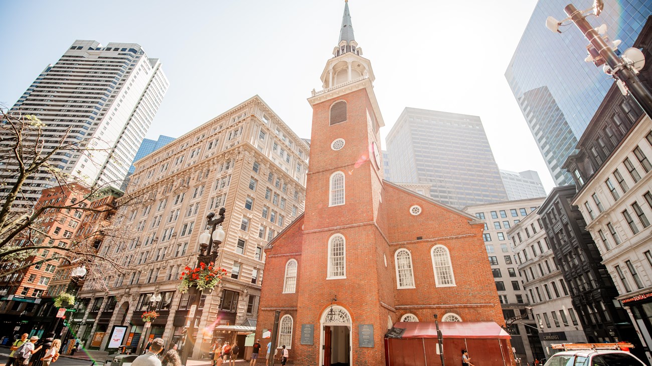 A brick two-story meeting house with a tall white steeple
