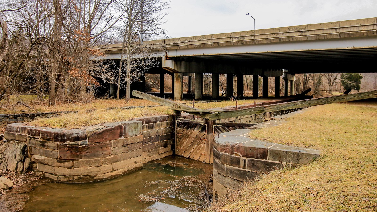 A watered lock sits under an overpass.