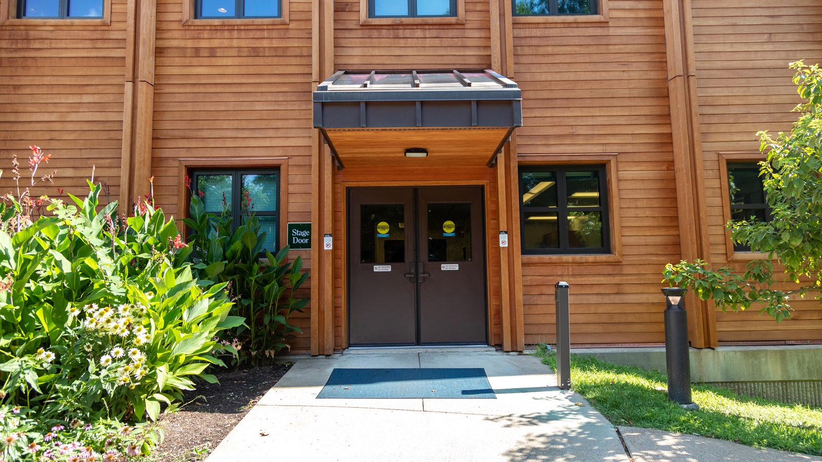 Path leads to double doors under an awning with a
