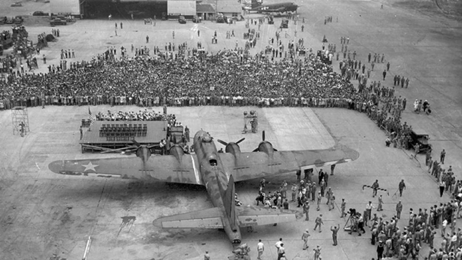 large plane with crowd of people in front of a hanger