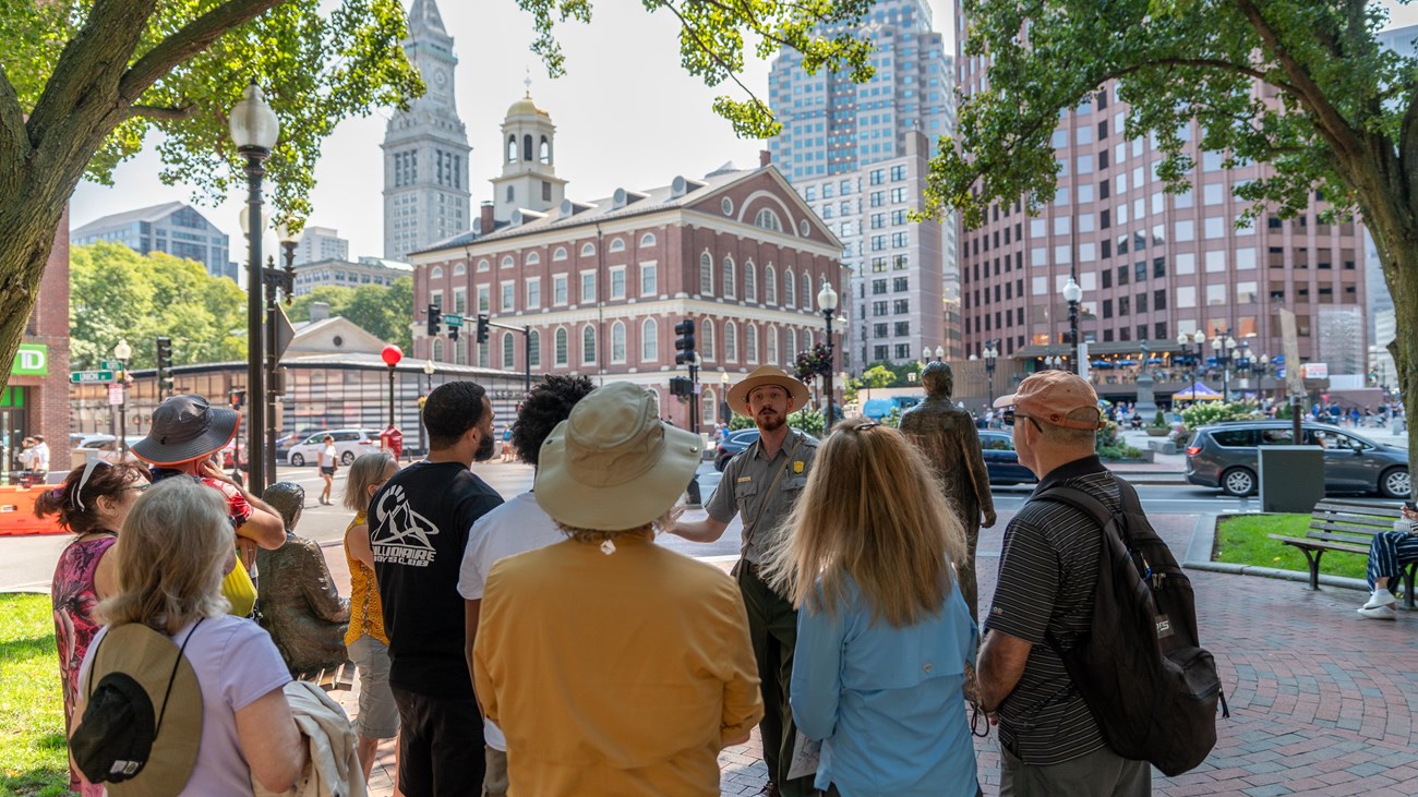 Ranger talking to a group of people. Faneuil Hall stands in the background.