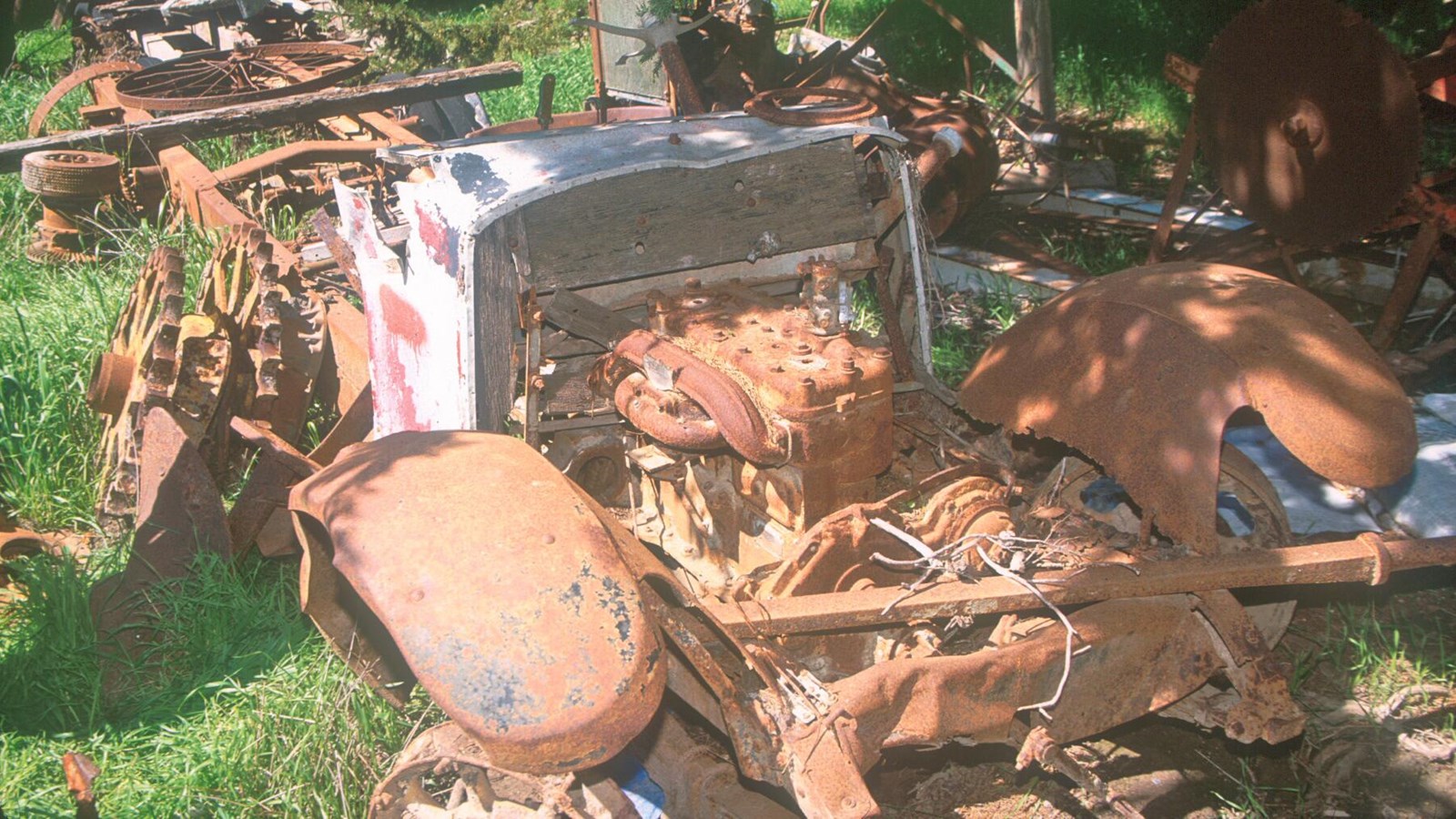 About the length of a delivery truck, only the frame with rusted tire rims, chassis, metal seat, ste