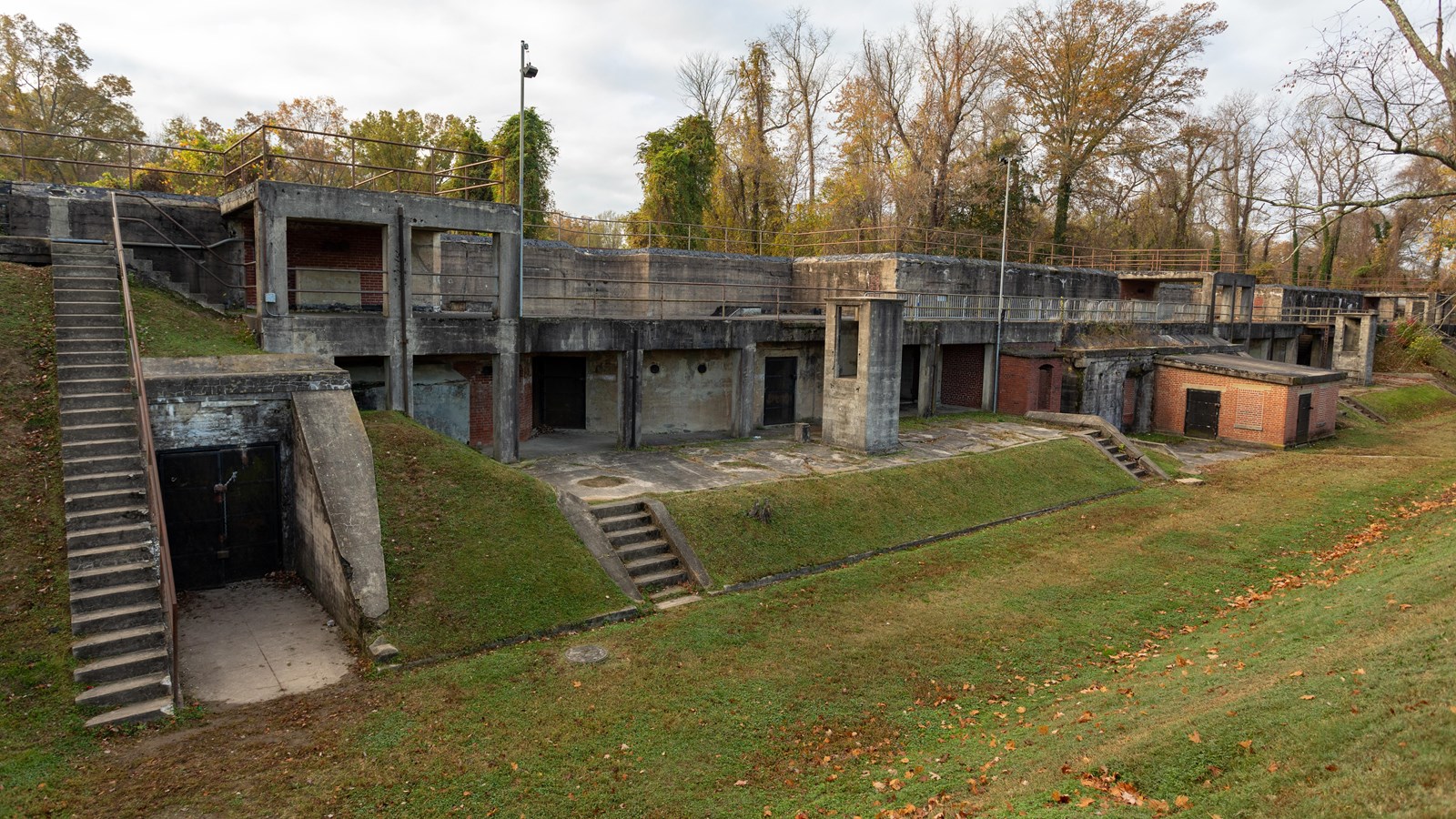 A concrete structure is positioned in the ground. Stairs lead to multiple doors and openings.