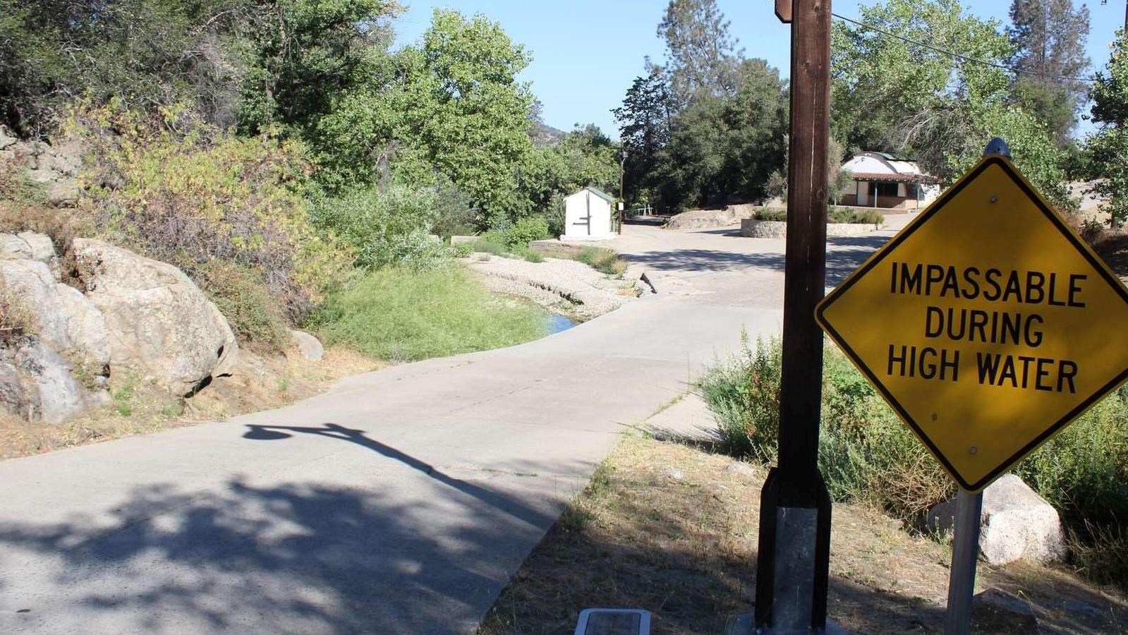 A yellow sign to the right of the walkway says,