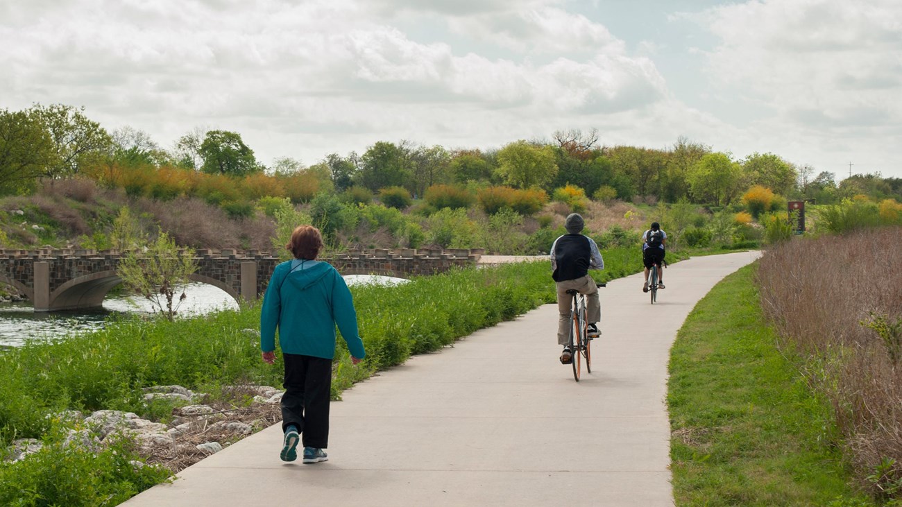 Two hikers and one bicyclist recreate on the Hike and Bike Trail next to the San Antonio River.