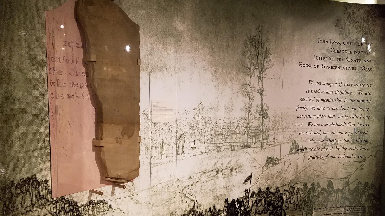 A large wall exhibit that displays images of people walking and different script.