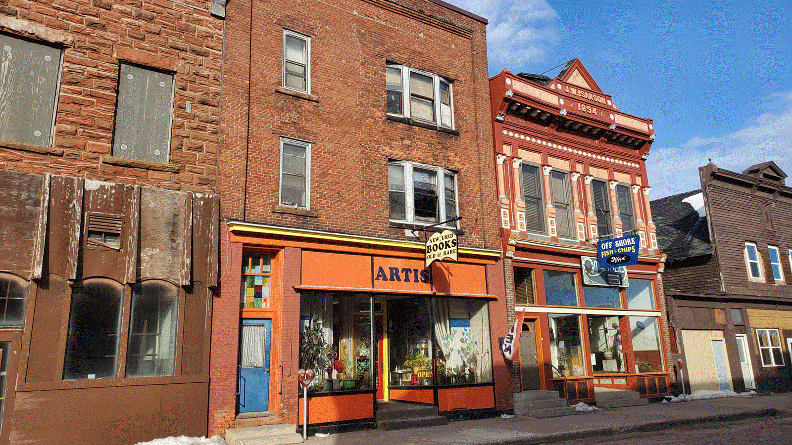 Three story red brick building with flat roof. Sign above the door reads: New, Used Books Old & Rare