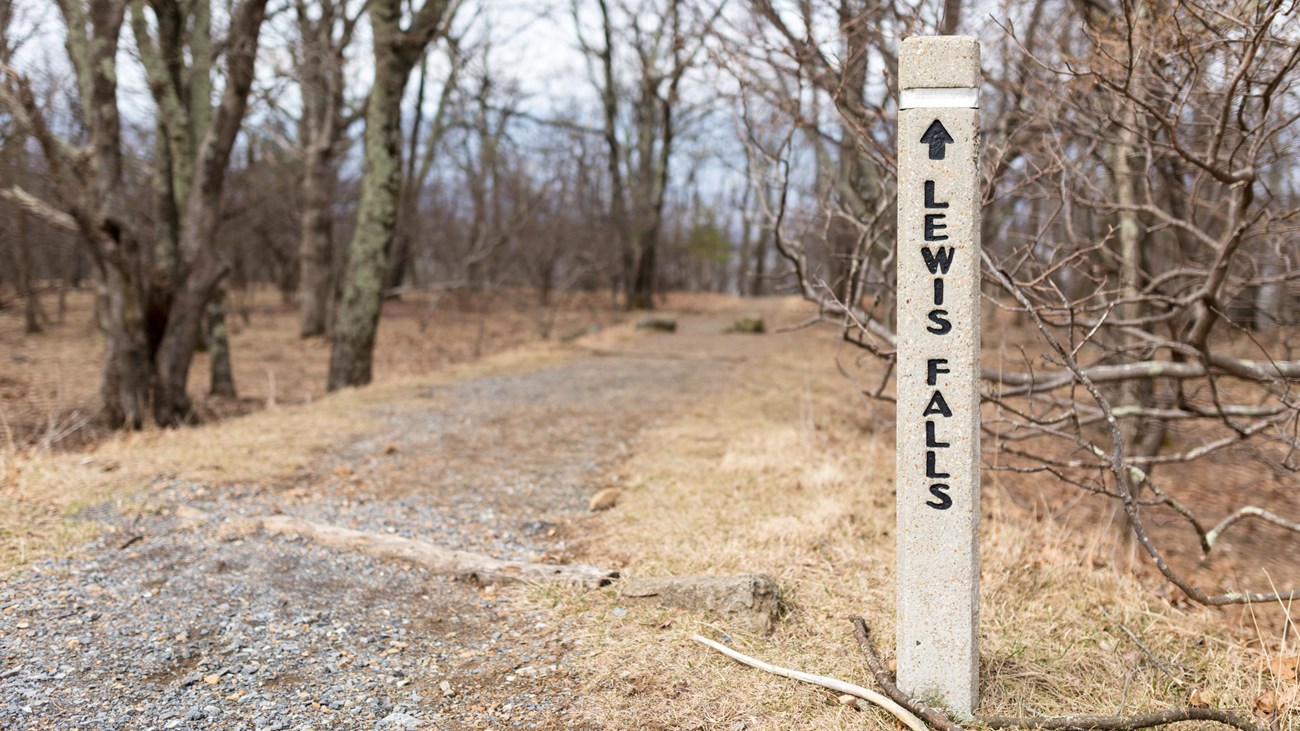 A concrete post at the head of a trail the reads Lewis Falls