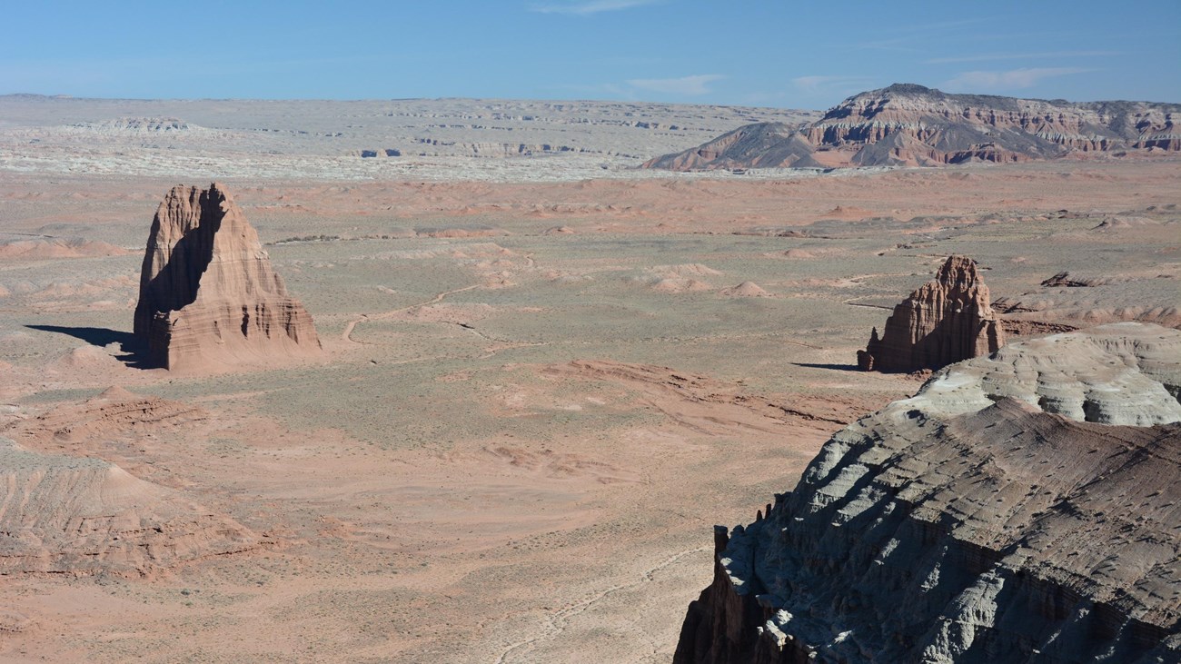 View looking down on triangular, reddish orange monoliths in a desert.