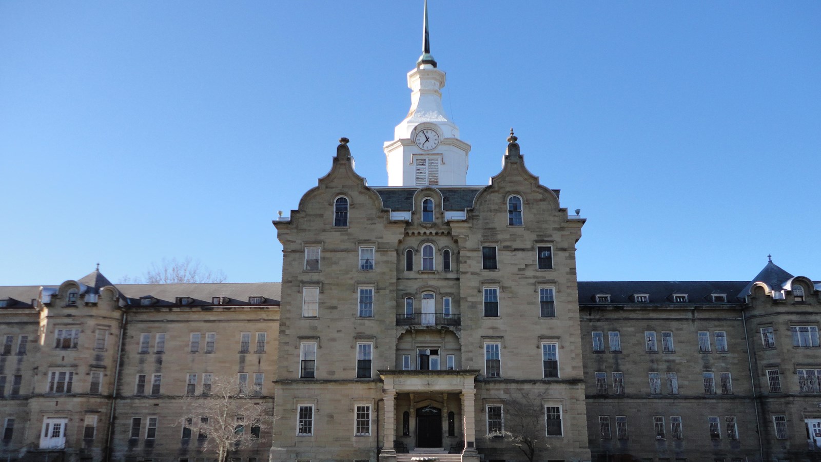 Large stone building with a clock tower on top and a fountain in front