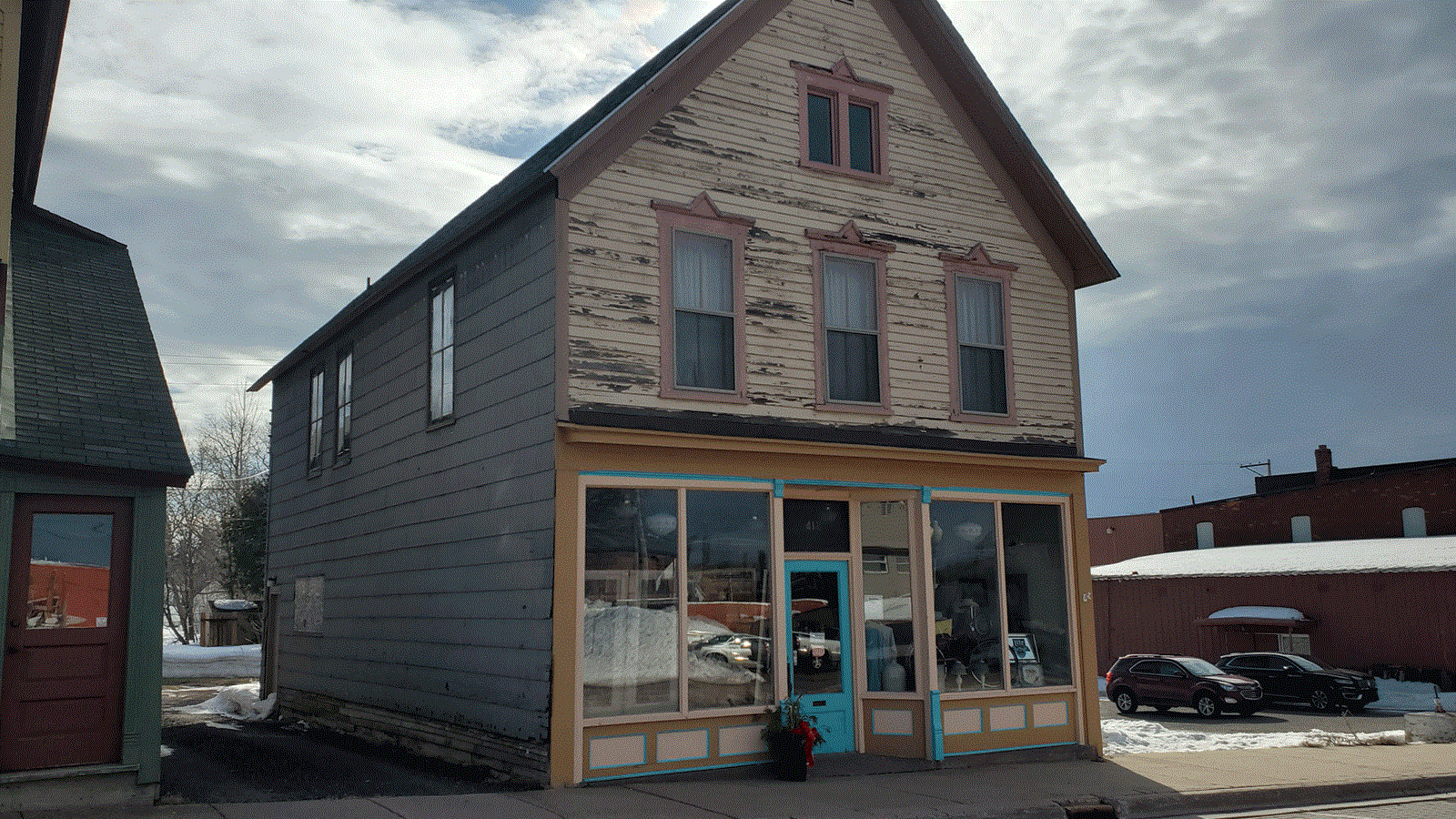 Two story wooden building with large windows and gabled roof.
