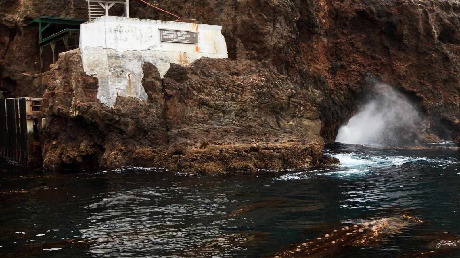 steep rocky cliffs with water shooting out of hole.