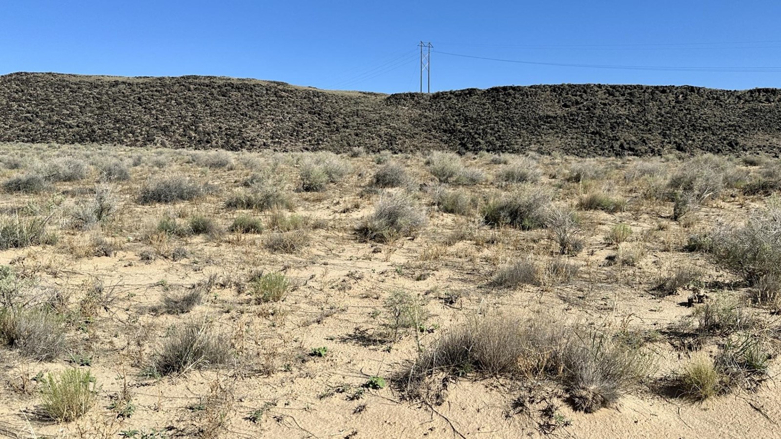 A desert and volcanic landscape under a blue sky.