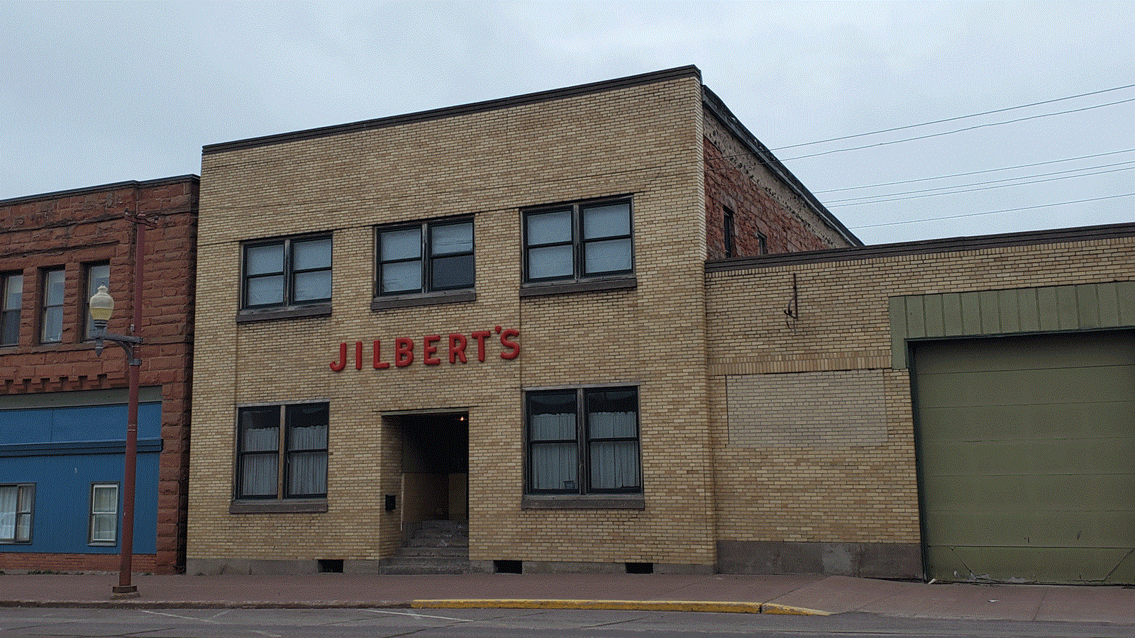 Two story yellow brick and red sandstone building with letters above the entrance reading: Jilbert\'s