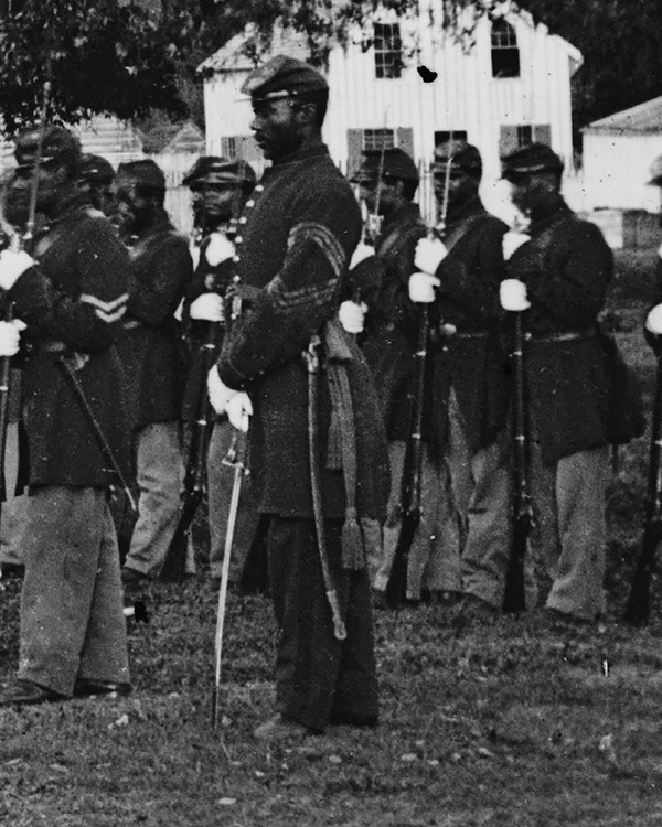 Civil War photo of Black soldiers, one is a Sgt Major at the end of the line, and holding a sword