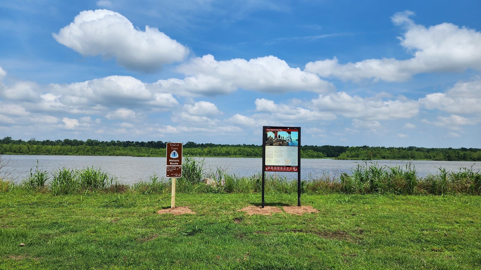 Trail of Tears exhibit and mileage sign sitting in the forefront along the riverfront and the lush, 