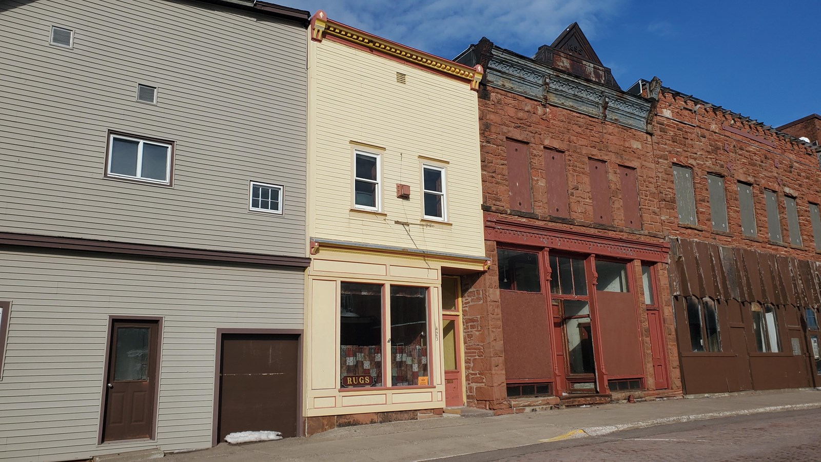 Two story building with cream-colored siding, flat roof, and small decorative cornice.