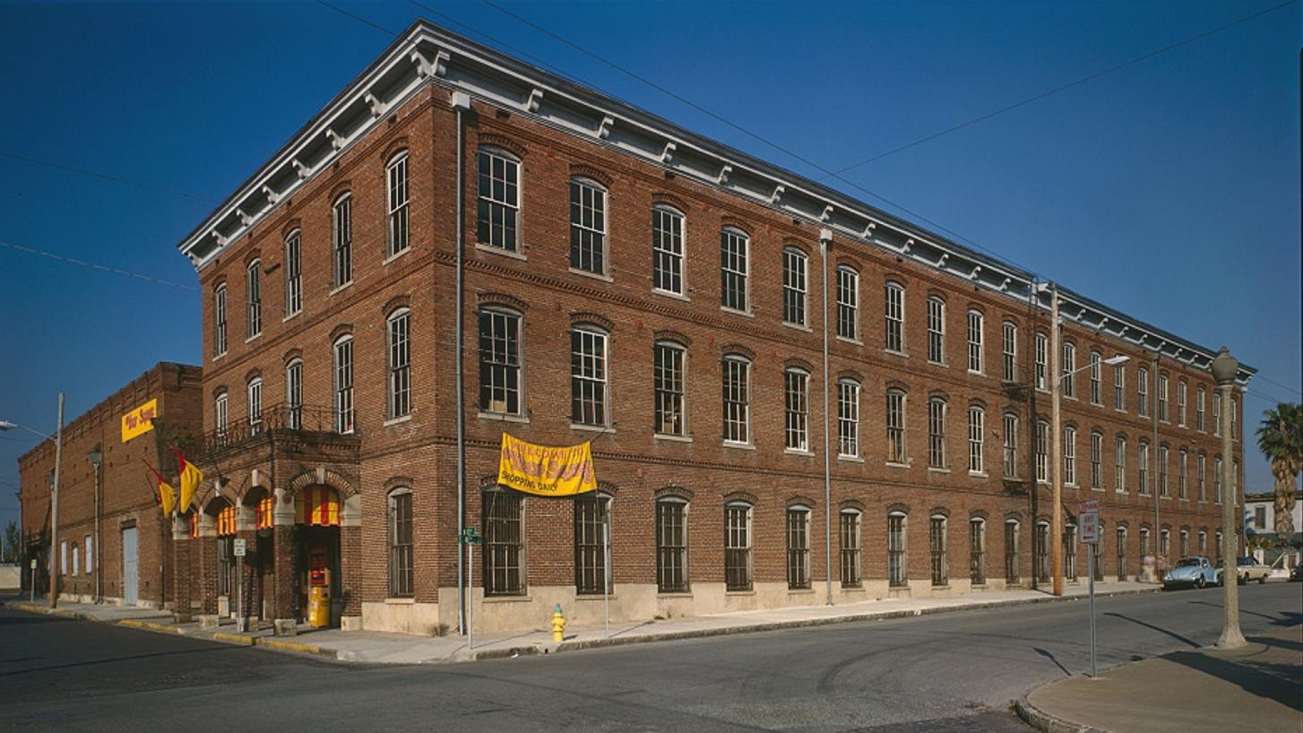 Red brick three story building with three arches over front door on a street corner.