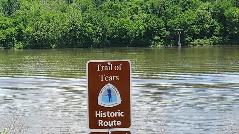 Trail of Tears mileage sign on edge of riverbank.