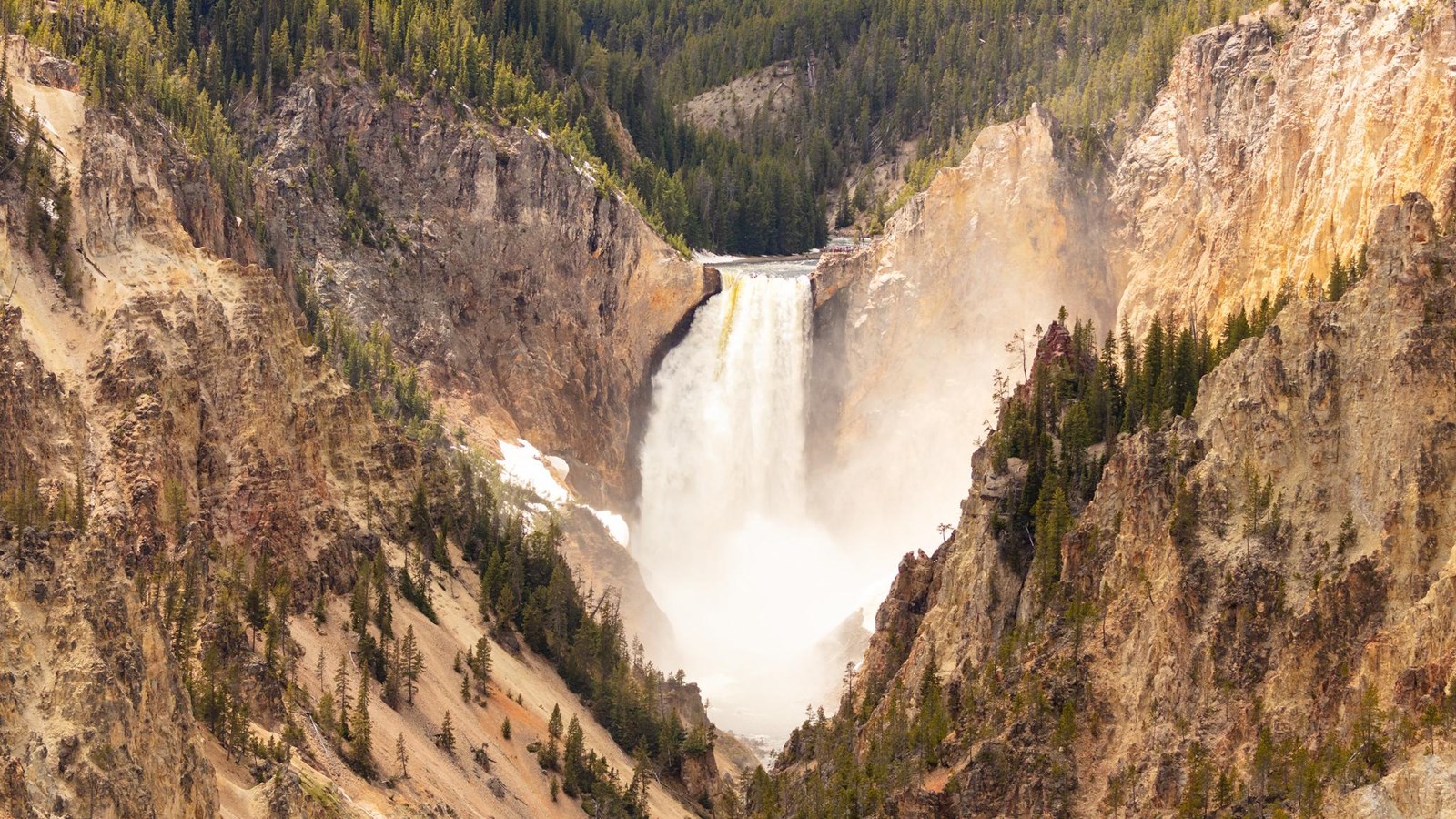 A 300 foot waterfall spills into a canyon colored in shades of yellow and gray.