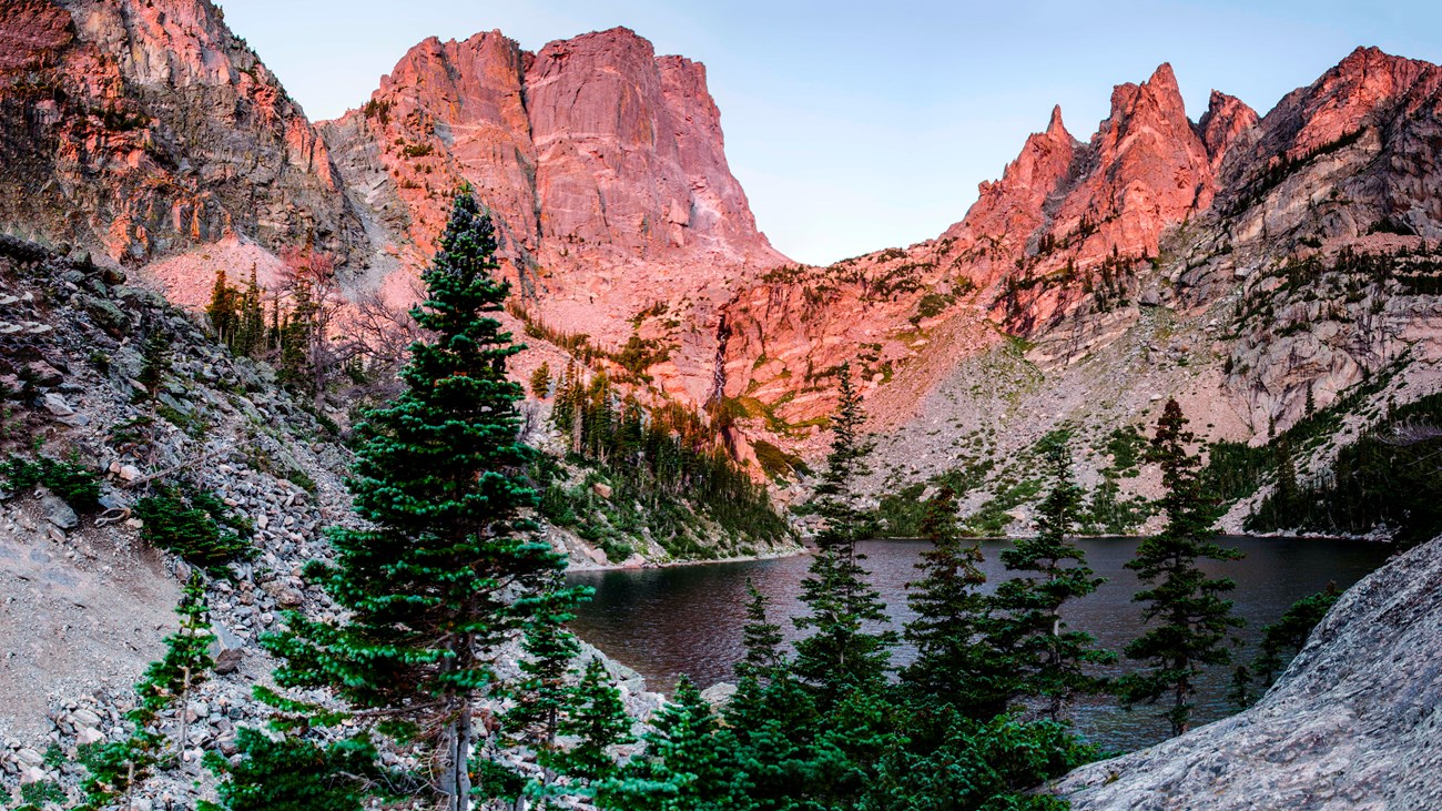 the sun shines on a mountain ridge and lake