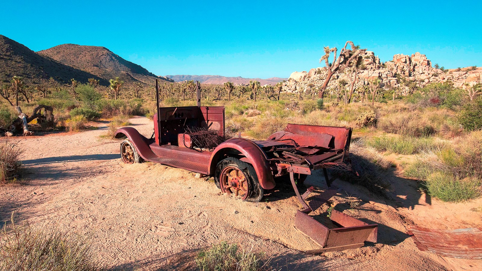 A rundown and rusty vehicle in the desert.