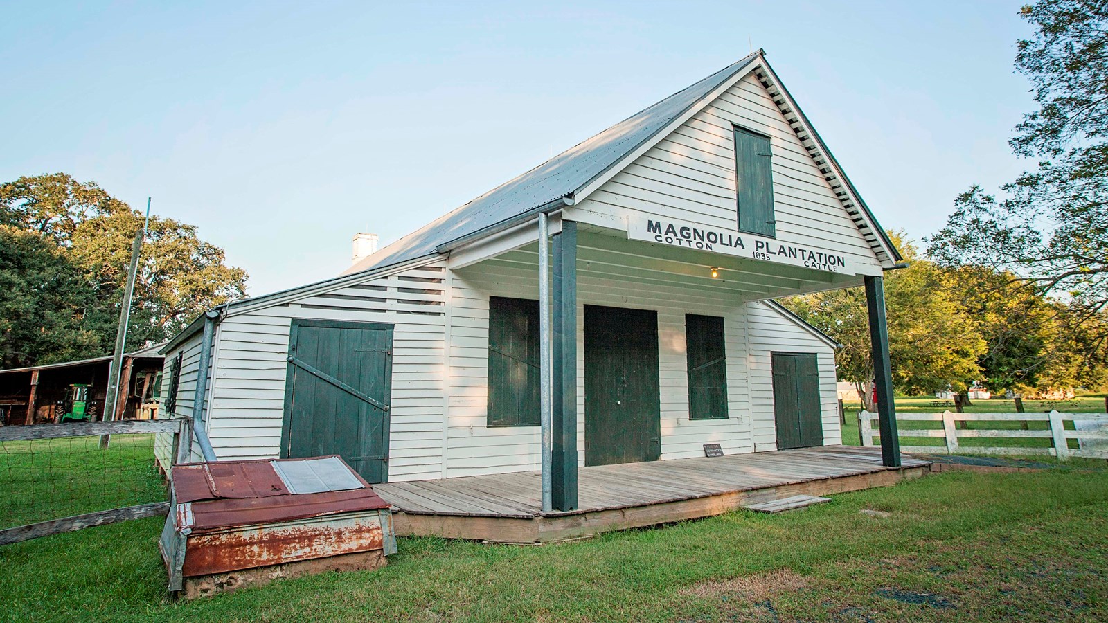A white building with green trim features a front porch with peaked roof.