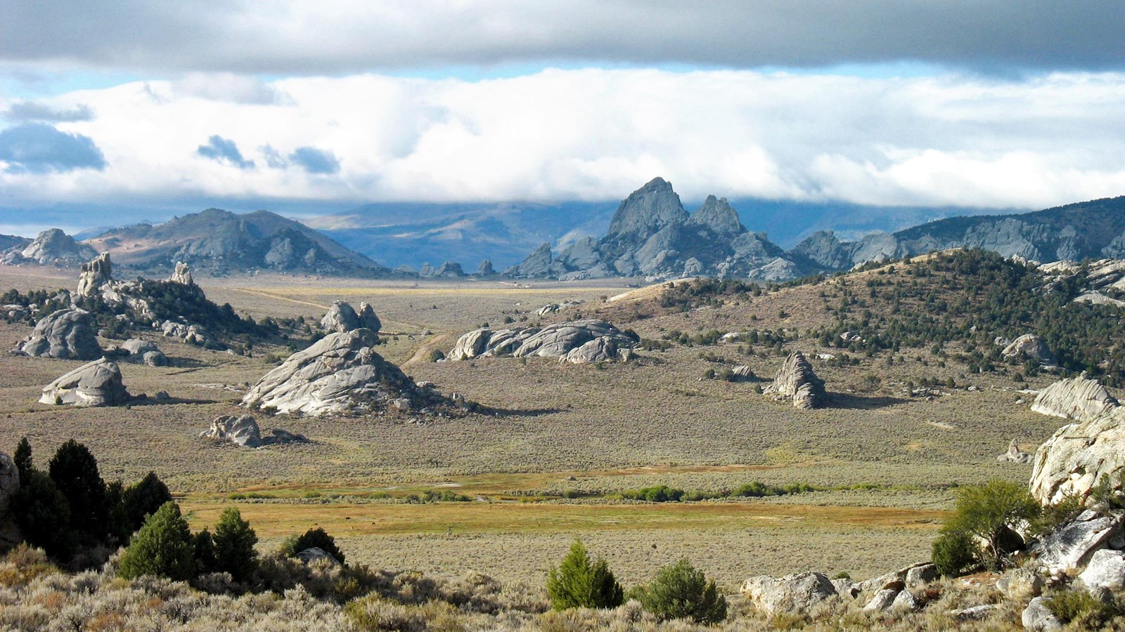 Cloudy overview with granite pinnacles jutting out around green meadows in Circle Creek Basin