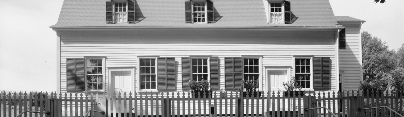 black and white photo of a white clapboard building with two doors