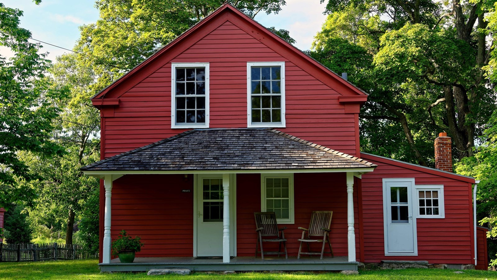 A red house with white trim and two white doors.